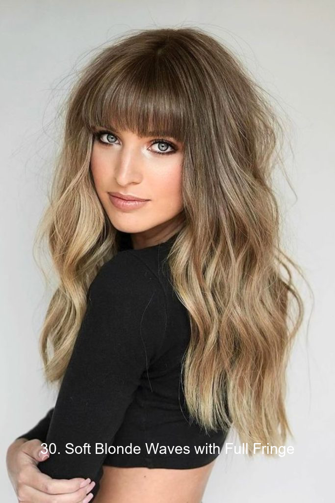 30. Soft Blonde Waves with Full Fringe